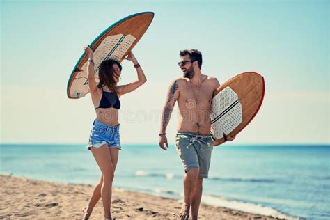 Surfers At The Beach Young Couple Of Surfers Walking On The Beach And