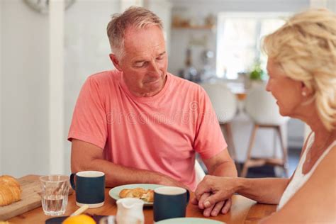 Senior Woman Comforting Man Suffering With Depression At Breakfast