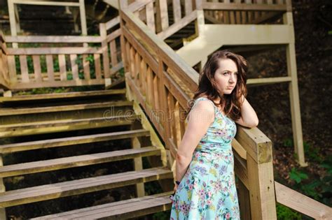 Menina Que Senta Se Nas Escadas De Madeira No Parque E No Sorriso Foto