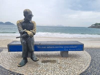 Estátua de Carlos Drummond de Andrade na praia de Copacabana tem os