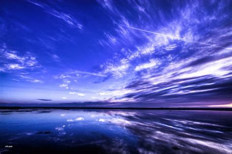 The Sky And Clouds Are Reflected In The Water