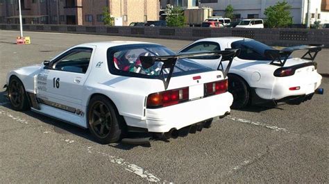 two white sports cars parked next to each other in a parking lot