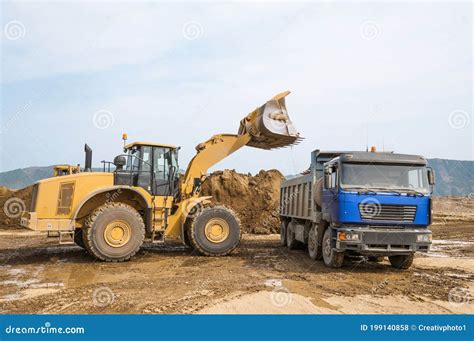 Wheel Loader Loads Clay Into The Bucket Of A Dump Truck Stock Photo