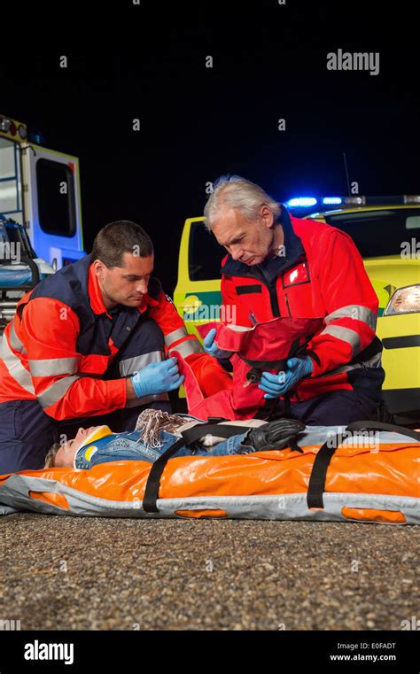 Paramedic Team Giving Firstaid To Injured Woman At Night Stock Photo