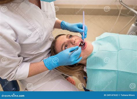 Dentist Hygienist Conducts A Teeth Cleaning Procedure For A Girl In A