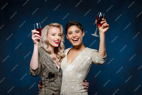 Free Photo Two Beautiful Women In Evening Dresses Smiling Holding Wine Glasses