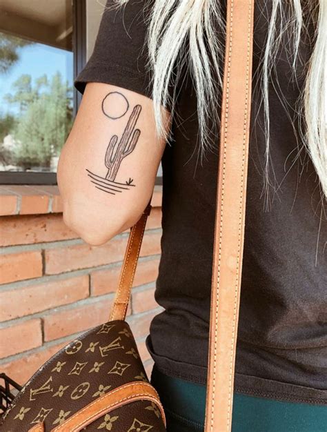 A Woman With A Tattoo On Her Arm Holding A Brown Louis Vuitton Bag