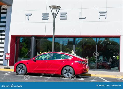 Red Tesla Vehicle Parked Outdoor In Front Of The Dealership Editorial