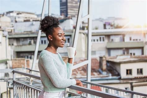 A Young Black Woman Is Having Coffee On The Balcony African American