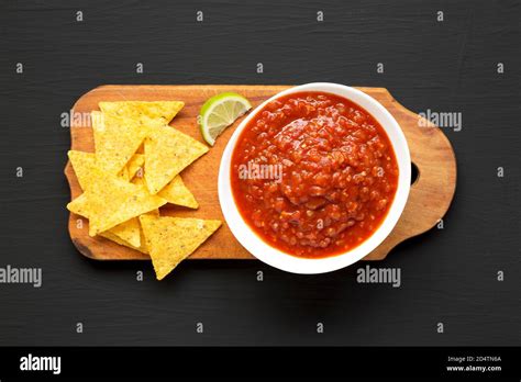 Homemade Tomato Salsa And Nachos On A Rustic Wooden Board On A Black