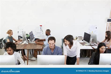 Colleagues Talking At Work In A Busy Open Plan Office Stock Image