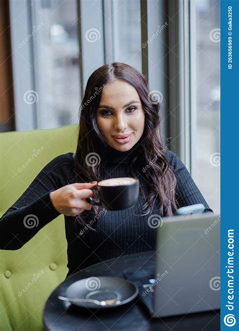 A Business Woman Is Sitting At A Table In The Office Talking On The Phone Working On A Laptop