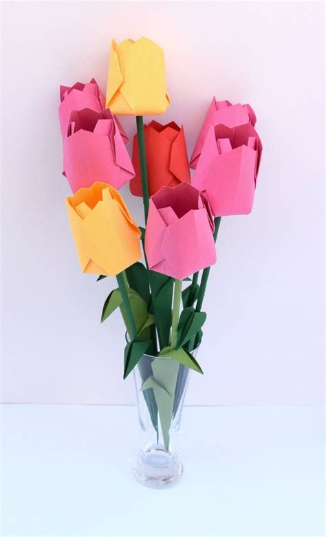 A Vase Filled With Paper Flowers Sitting On Top Of A White Table Next To A Wall