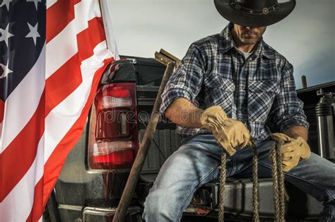 Cowboy Rancher Seating On His Pickup Truck Cargo Bed With A Rope In His