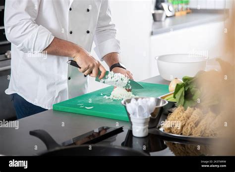 Crop Man In White Chef Jacket Using Knife For Cutting Onion While