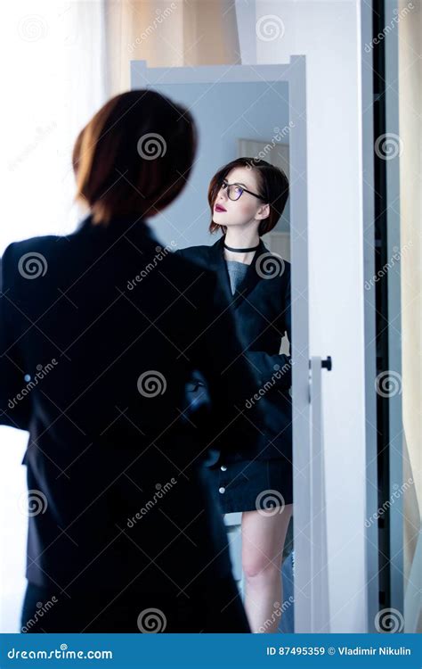 Beautiful Young Woman Standing In Front Of Mirror And Looking At Stock