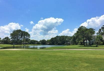 A Golf Course With Water And Trees In The Background