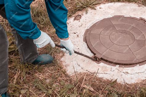 Premium Photo A Worker Opens A Well Hatch With A Pry Bar