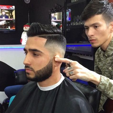 A Man Cutting Another Mans Hair In A Barbershop With An Army Uniform On