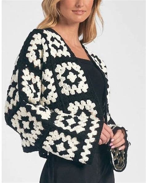 A Woman Wearing A Black And White Crochet Cardigan With Flowers On It