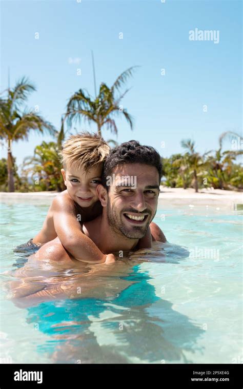 Portrait Of Happy Biracial Father And Son Playing Together In Swimming