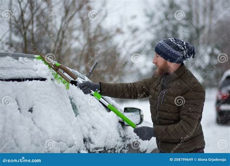 Man Cleaning His Car From Snow With A Brush In A Winter Day Stock Image