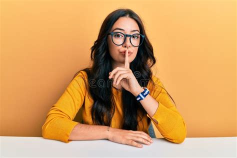 Beautiful Brunette Young Woman Wearing Glasses And Casual Clothes Sitting On The Table Asking To