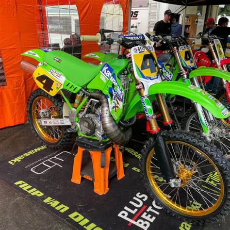 Two Green Dirt Bikes Parked Next To Each Other On A Black And Orange