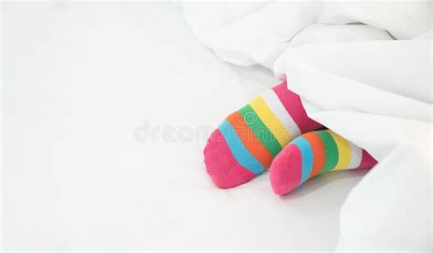 Female Foot In Warm Stripe Wool Sock Woman Sleeping And Relaxing In Bed Concept Warm And Cozy