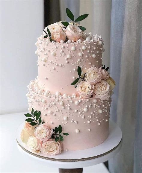 A Three Tiered Pink Wedding Cake With Flowers On Top