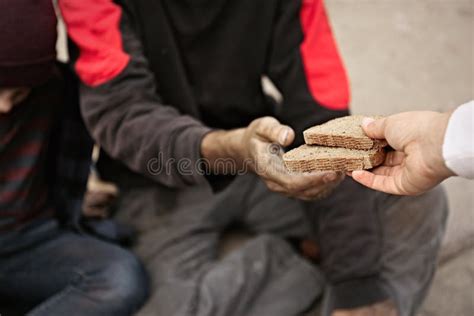 Woman Giving Poor Homeless People Pieces Of Bread Outdoors Stock Photo