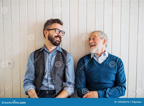 A Portrait Of Adult Hipster Son And Senior Father Sitting On Floor