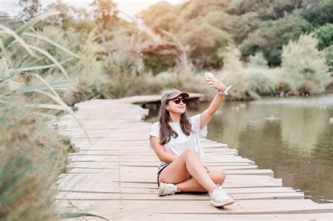 Jovem Latina Tirando Selfies Celular E Sorrindo Em Uma Ponte De Madeira Foto Premium