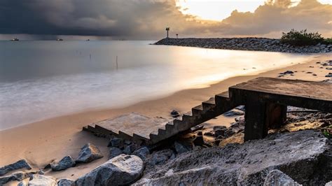 Uma Praia C U Nublado E Um Cais Um Farol Ao Fundo Foto Premium