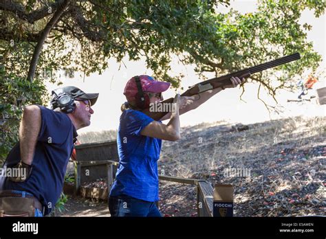 Caucasian Woman Shooting Clays With A Shotgun With Instructor Teaching