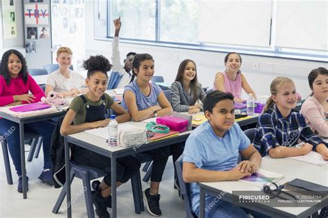 Junior High School Students Enjoying Lesson At Desks In Classroom