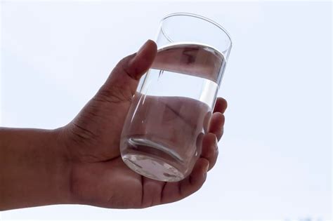 Premium Photo Cropped Hand Of Man Holding Water In Glass Against White Background