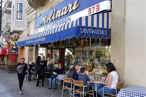 People Are Sitting At Tables In Front Of A Store With Blue And White