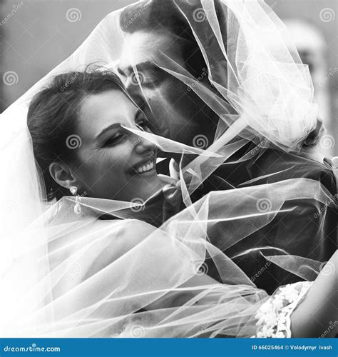 Handsome Groom And Beautiful Bride Kissing Under Veil In Old Street