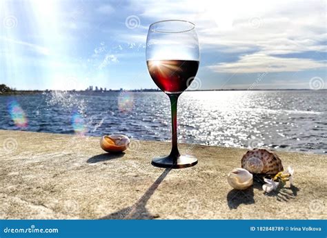 Glass Of Red Wine On Beach Stone And Seashells Nature Panorama Blue Sky And Sea Water Sunlight