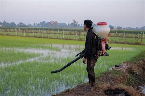 Premium Photo A Farmer From Asia Is Using A Knapsack Mist Duster To