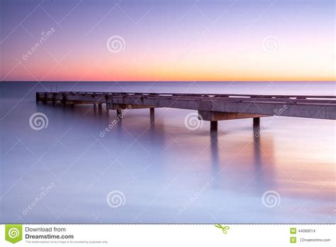 Jetty In The Sunrise With Still Sea Water Stock Photo Image Of