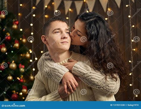 Young Couple In Christmas Lights And Decoration Dressed In White Fir Tree On Dark Wooden