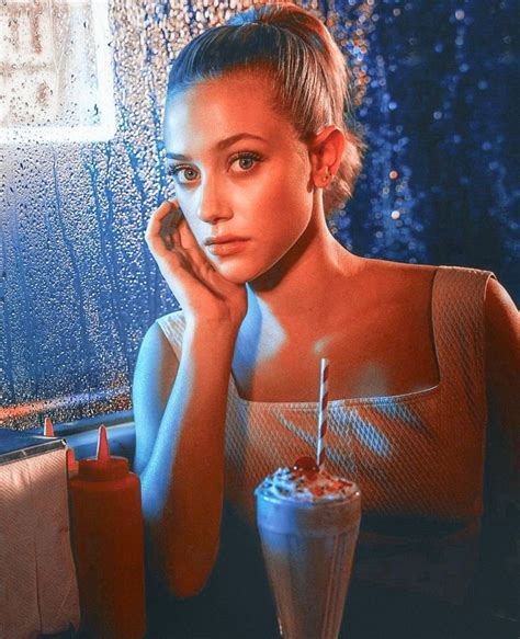 a woman sitting in front of a window next to a drink