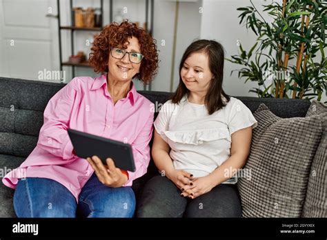 Mature Mother And Down Syndrome Daughter At Home Using Touchpad Device