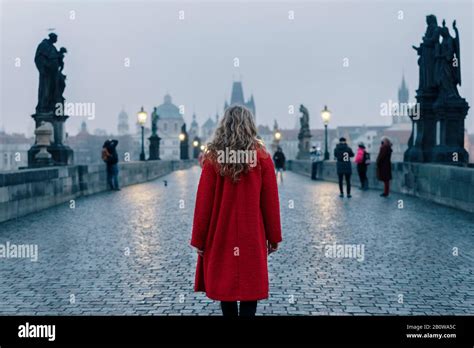 Female Tourist Walking Alone On The Charles Bridge During The Early Morning In Prague Capital