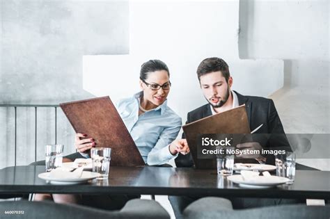 Young Businesswoman And Businessman Browsing Menu In Restaurant At