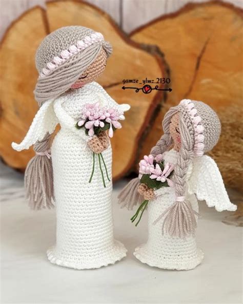 Two Crocheted Angel Figurines With Flowers In Their Hands One Holding