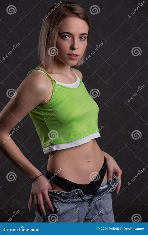 Gorgeous Blonde Girl In A Crop Top And Jeans Poses On A Dark Background Stock Photo Image Of