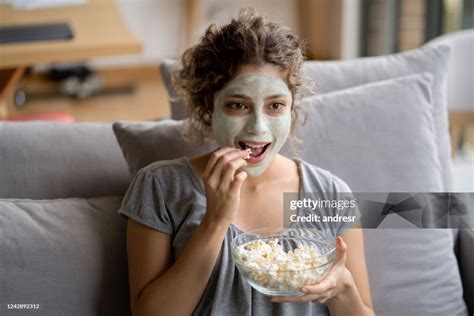 Woman Relaxing At Home Trying A Facial Mask And Eating Pop Corn While